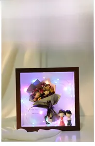Detail view of wooden shadow box with dried roses, LED fairy lights and couple figurines