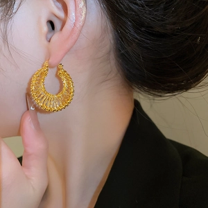 Detailed close-up of 18k gold-plated hollow woven hoop earrings with intricate metal texture