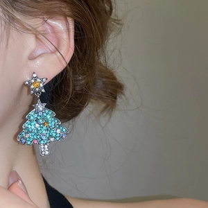 Gros plan de boucles d'oreilles sapin de Noël avec des cristaux colorés portées