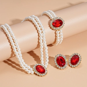 Three-piece jewelry set with red oval stones and pearls on elegant display cylinders