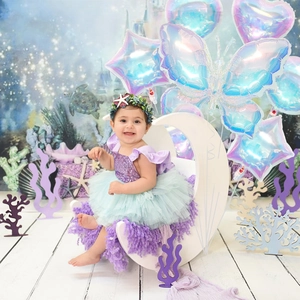 Mermaid baby costume set with purple sequin top and green tutu among butterfly balloons
