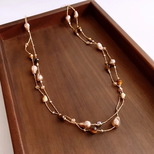 Close-up of double-layer necklace with amber tiger eye beads and pearls on wood