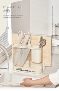 Close-up of cream kitchen organizer with transparent knife slots and cutting board rack