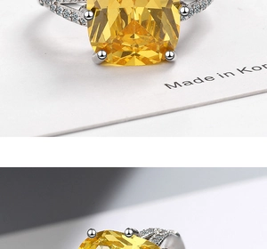 Detail of silver ring featuring a large square yellow gemstone and small white side stones