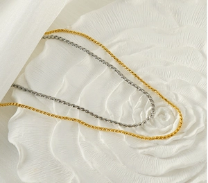 Detail shot of minimalist stainless steel twist chains in gold and silver on a white plate
