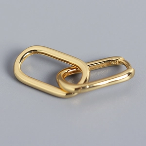 Close-up of interlocking gold oval hoops with S925 hallmark on polished metal surface