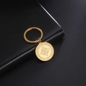 Golden stainless steel Wicca knot Celtic pendant keychain on black leather background