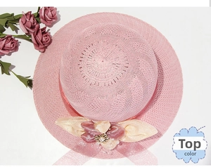 Close-up of pink straw hat top with silk bow, pearls and vintage flower buckle