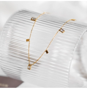 Detailed macro view of gold tassel necklace with crystal pendants on a textured glass