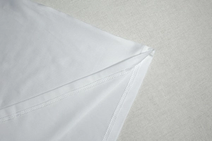 Gros plan de l'ourlet à double surpiqûre d'une robe en tricot blanc élégante