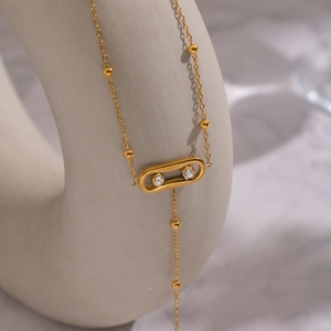 Détail d'une chaîne dorée avec pendentif ovale et deux pierres de zircon brillants