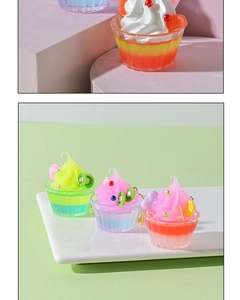 Macro shot of miniature fruit sundae charms with cream textures and gold chain accents