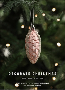 Detail of pink pine cone Christmas ornament with glitter edges on a holiday tree