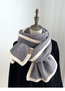Detail of grey knitted scarf with white stripes and stitched brown leather label