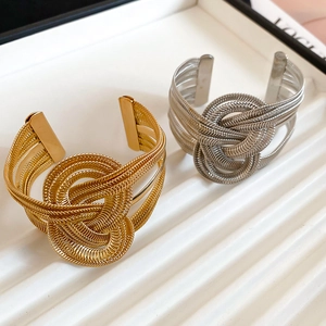 Detail of gold and silver multi-layer cuff bracelets with intricate metal knot design