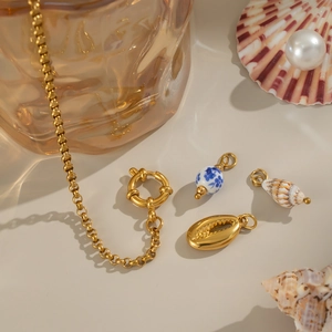 Detailed shot of golden shell and ceramic pendants on jewelry over a seaside theme backdrop