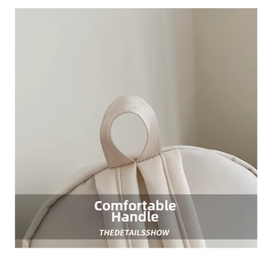 Dettaglio dell'impugnatura in tessuto rinforzato dello zaino beige dallo stile minimalista