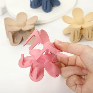 Floral matte hair claw clips in macaron colors shown in hand for versatile hairstyling