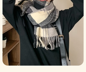 Close-up detail of a thick plaid scarf featuring soft fringe edges and a warm knit texture