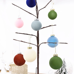 Close-up of velvet flocked Christmas balls in various matte colors hanging on a tree