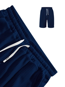 Detail of waffle knit fabric and elastic waistband with white drawstring on men's blue shorts