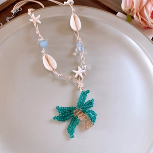 Detailaufnahme einer bunten Perlenkette mit Blumenanhänger, Muscheln und Seestern-Anhängern