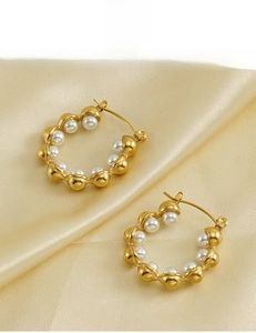 Detail of 18k gold plated hoop earrings with white pearls on champagne silk background