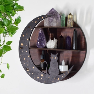 Detail of wooden crescent moon cat shelf with crystals and candles on white wall