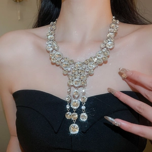 Close-up of sparkling rhinestone tassel necklace worn by a model on black dress