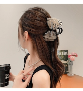 Détail d'une pince à cheveux en dentelle beige à pois noirs sur une coiffure élégante