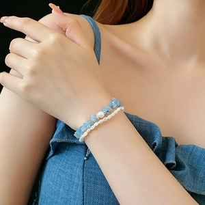 Gros plan d'un bracelet en aigue-marine avec perle d'eau douce sur le poignet