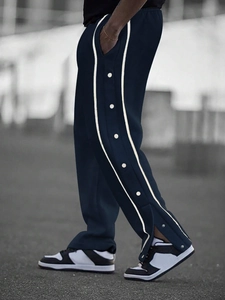 Detail view of men's navy jogger pants with side buttons and white contrast stripes