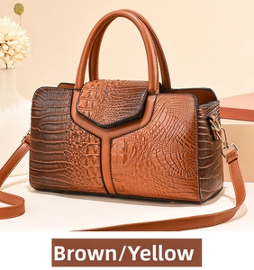 Detail of tan crocodile pattern boston handbag with Y-shaped design and gold hardware