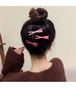 Vue détaillée de jolies pinces à cheveux rose en croix portées, accessoire de mode.