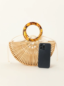 Detail view of semi-circular bamboo handbag with acrylic handle and phone for size reference