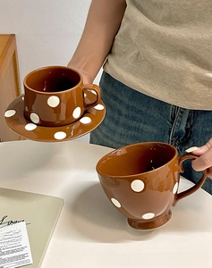 Détail d'une tasse à café vintage en céramique marron et soucoupe à pois blancs
