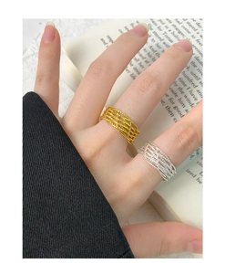 Close-up of elegant gold and silver woven multi-layer rings worn by a model