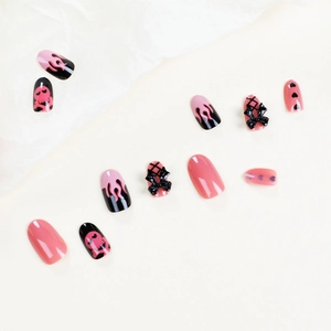 Pink and black flame skull press-on nails with 3D bows and heart patterns on beige background