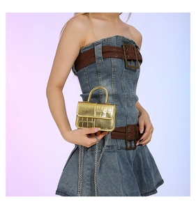 Golden mini handbag with crocodile texture and silver chain strap shown with denim outfit