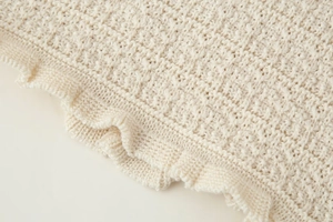 Gros plan sur un tricot crème avec des bords ondulés délicats et une texture douce