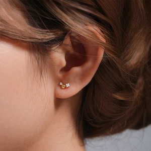 Macro shot of gold ear studs with round and square cubic zirconia on female model