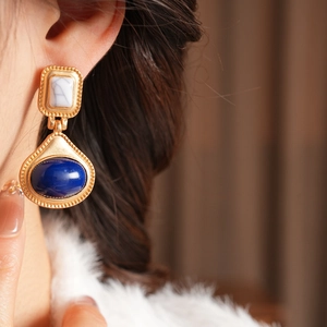 Close-up of vintage resin earrings with blue oval and marble pattern stones on model
