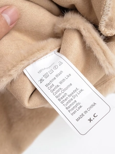 Detail of 100% polyester fabric texture and care label on camel fleece hooded vest