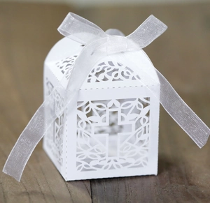 Detailed laser-cut white favor box with cross design and white organza ribbon bow