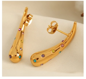 Macro detail of 18K gold plated teardrop earrings with multi-colored crystals on fabric