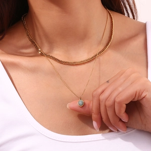 Close-up of a layered gold chain necklace featuring an oval grey natural stone pendant