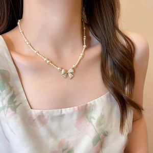 Elegant pearl choker necklace with a sparkling crystal bow pendant on female model