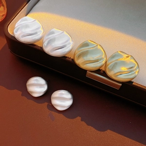 Detail of matte gold and silver rippled earrings displayed on a jewelry box edge