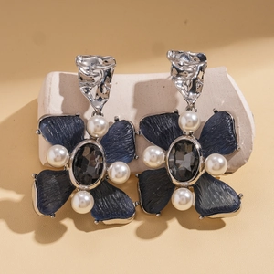 Macro shot of vintage resin flower earrings with grey gemstones and pearl accents