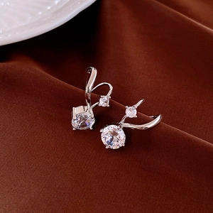 Macro shot of silver zircon butterfly tassel earrings on dark brown velvet fabric